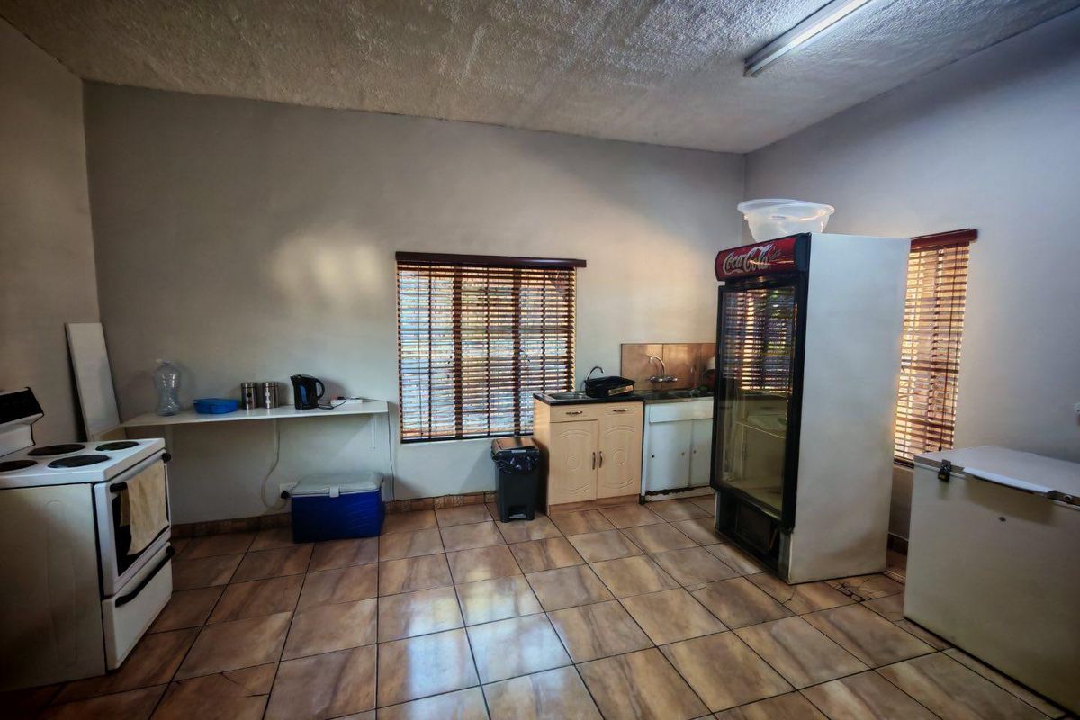 A functional industrial kitchen space featuring tiled flooring, basic cabinetry, and built-in sink area, suitable for utility or staff preparation purposes.