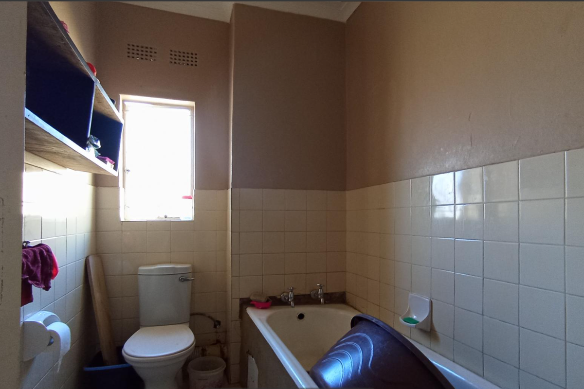 A functional bathroom featuring a standard bathtub, toilet, and tiled wall finishes, requiring cosmetic updates to modernize the space.