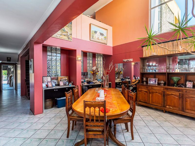 Spacious dining area featuring double volume ceilings, high-level windows for natural light, glass block accents, and ceramic tiled flooring.
