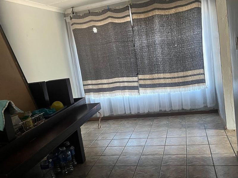 A living area featuring tiled flooring and a ceiling-mounted spotlight fixture, currently requiring cosmetic updates to improve its overall appeal.