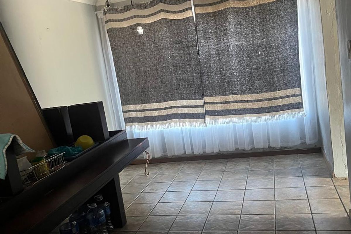 A living area featuring tiled flooring and a ceiling-mounted spotlight fixture, currently requiring cosmetic updates to improve its overall appeal.