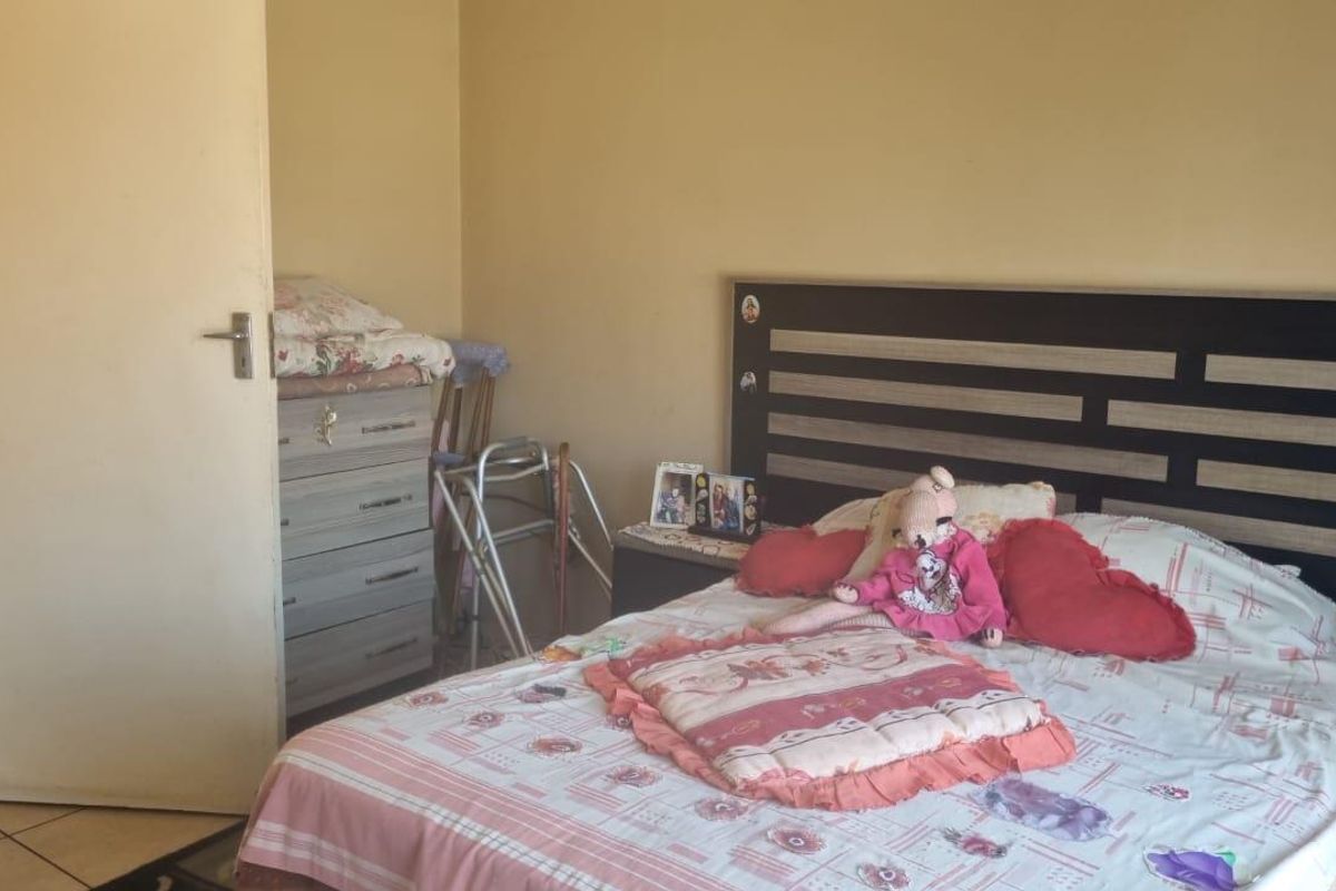A functional bedroom featuring tiled flooring and a built-in headboard, offering a neutral base for personalization.