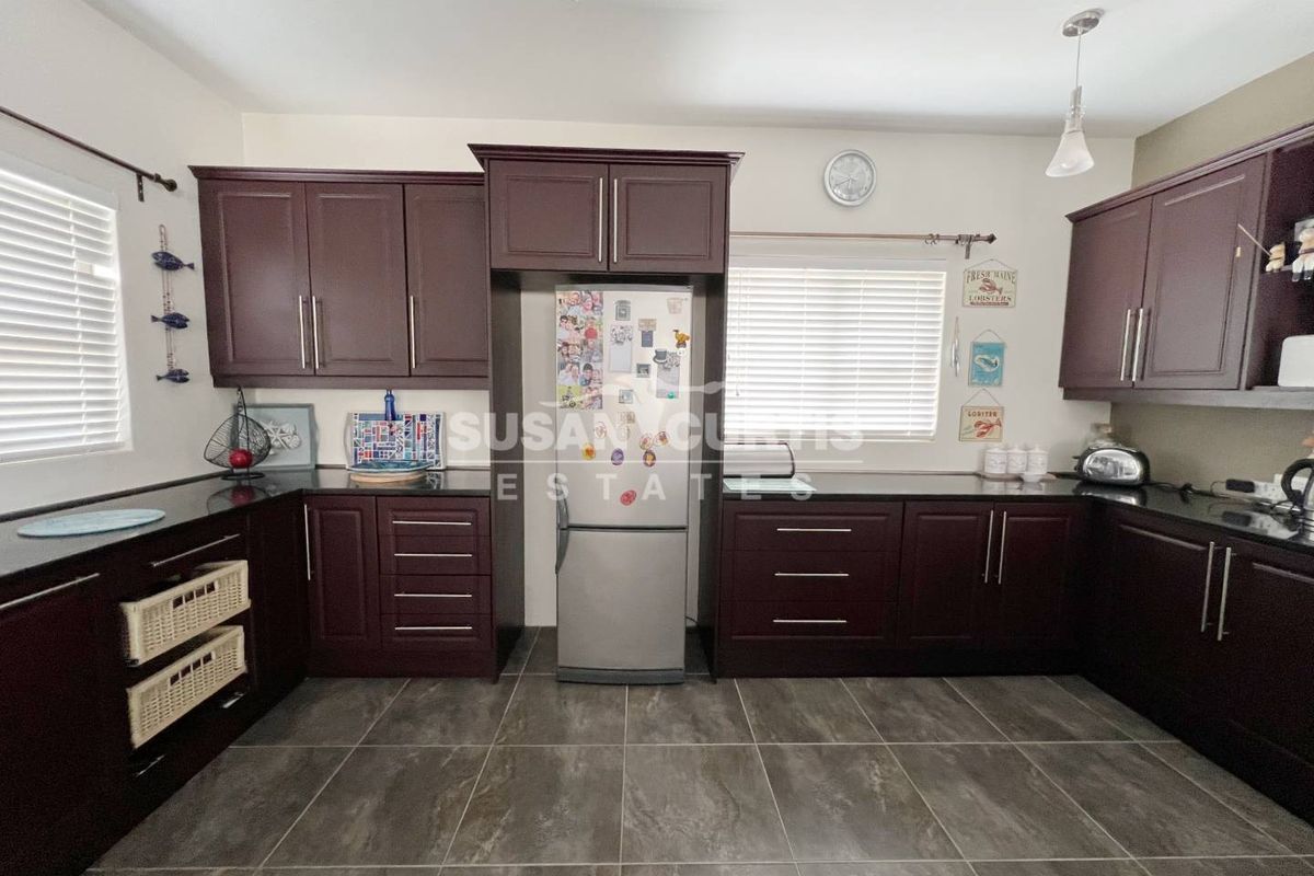 A functional kitchen featuring dark wood cabinetry, contrasting dark countertops, and tiled flooring, providing ample storage and workspace.