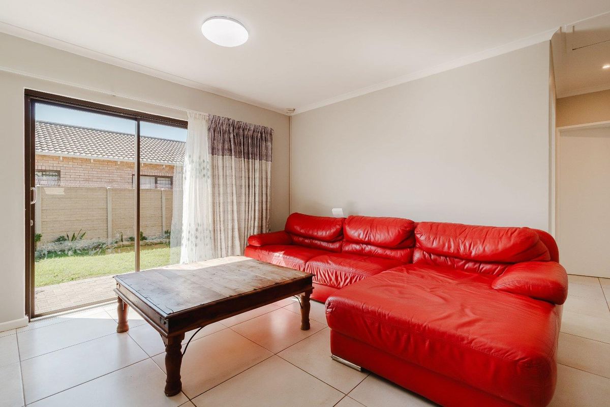 A bright living room featuring tiled flooring and a large sliding glass door providing direct access to the rear garden area.