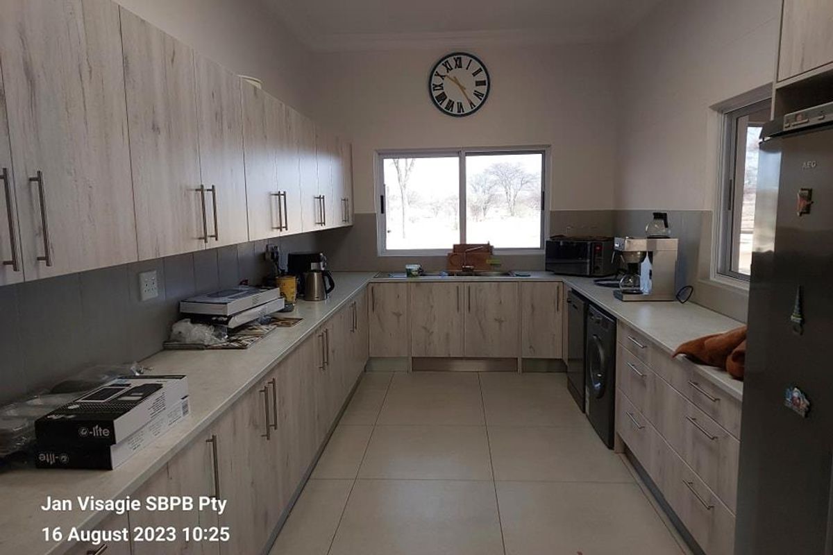 A functional kitchen featuring light wood-grain cabinetry, tiled flooring, and ample counter space with integrated appliance connections.