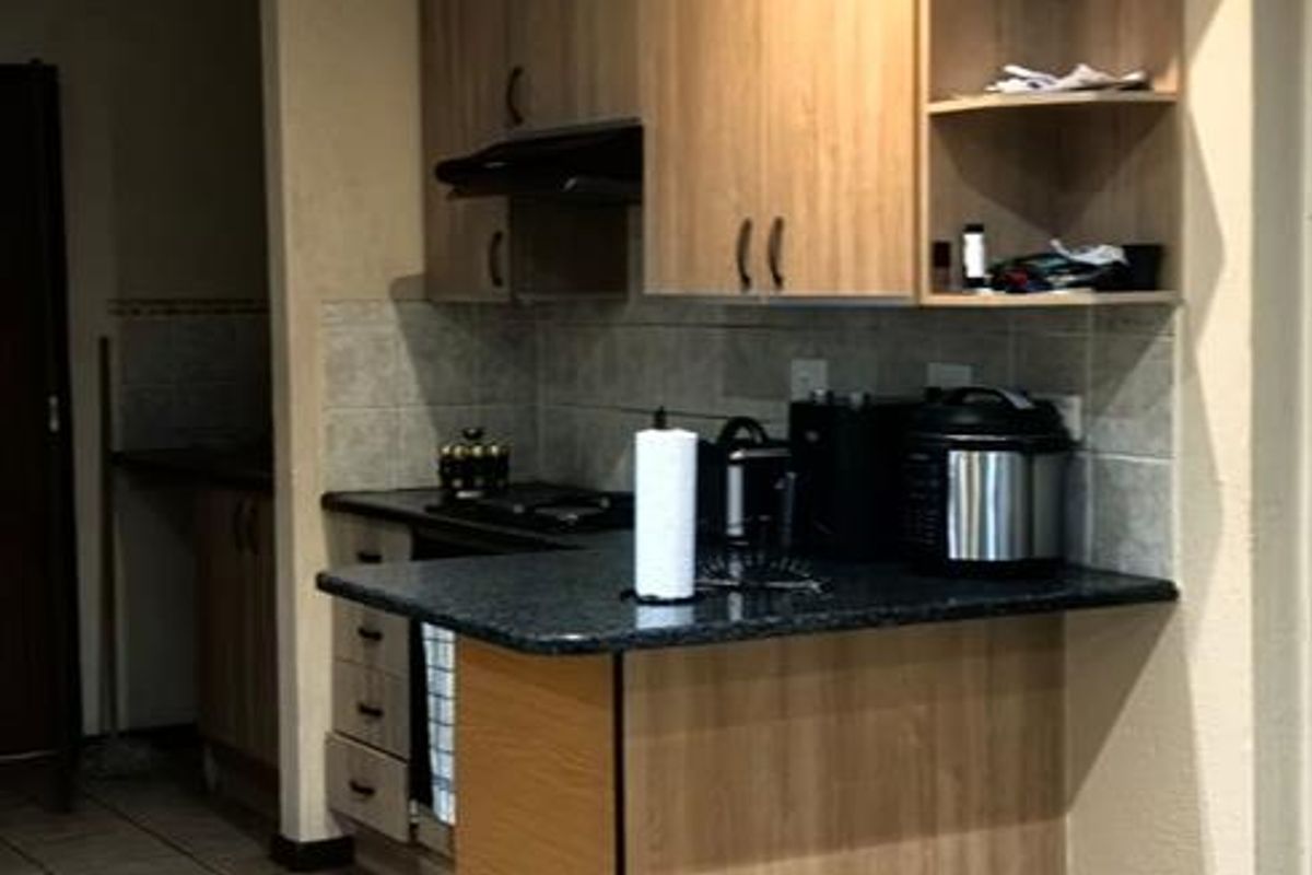 A functional kitchen featuring laminate cabinetry, granite countertops, and tiled flooring, offering a practical layout with integrated storage and workspace.