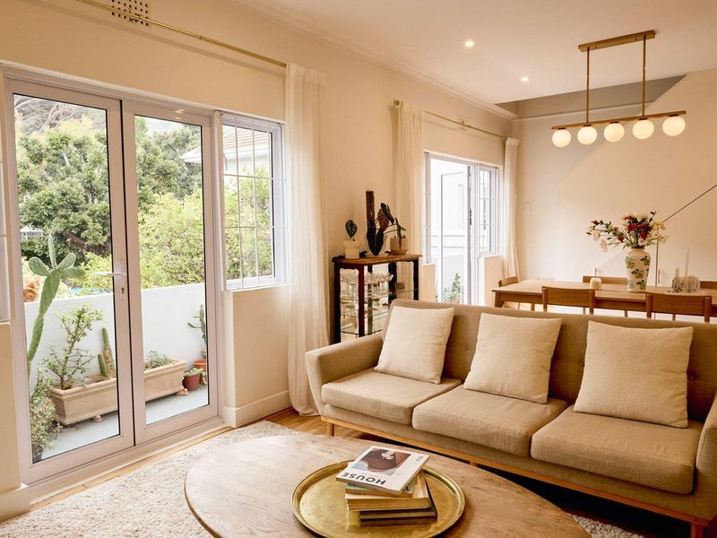 Bright open-plan living and dining area featuring hardwood floors, recessed lighting, and direct access to a private balcony through large glass doors.