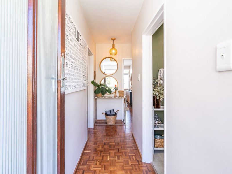 A bright hallway featuring classic parquet flooring and a warm pendant light, providing access to adjacent rooms within the apartment.