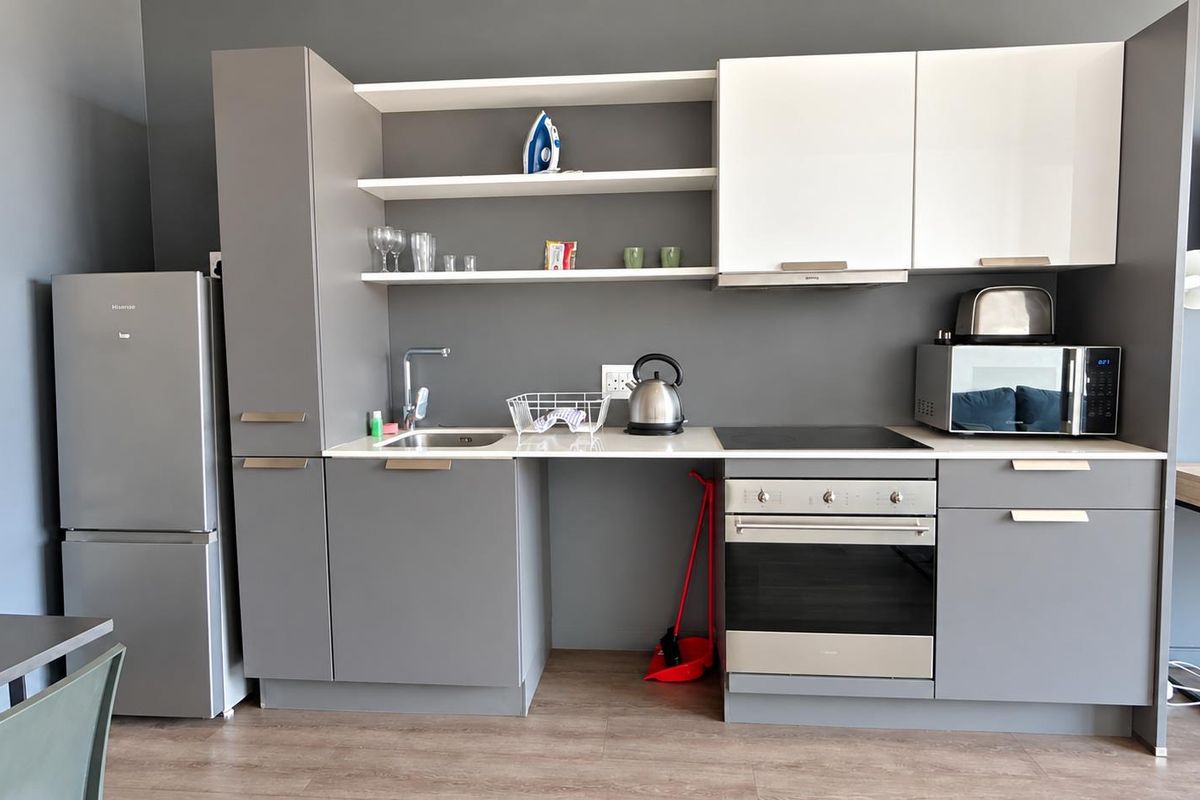 Modern kitchen featuring grey and white cabinetry, integrated appliances including an oven and hob, and open shelving for storage.