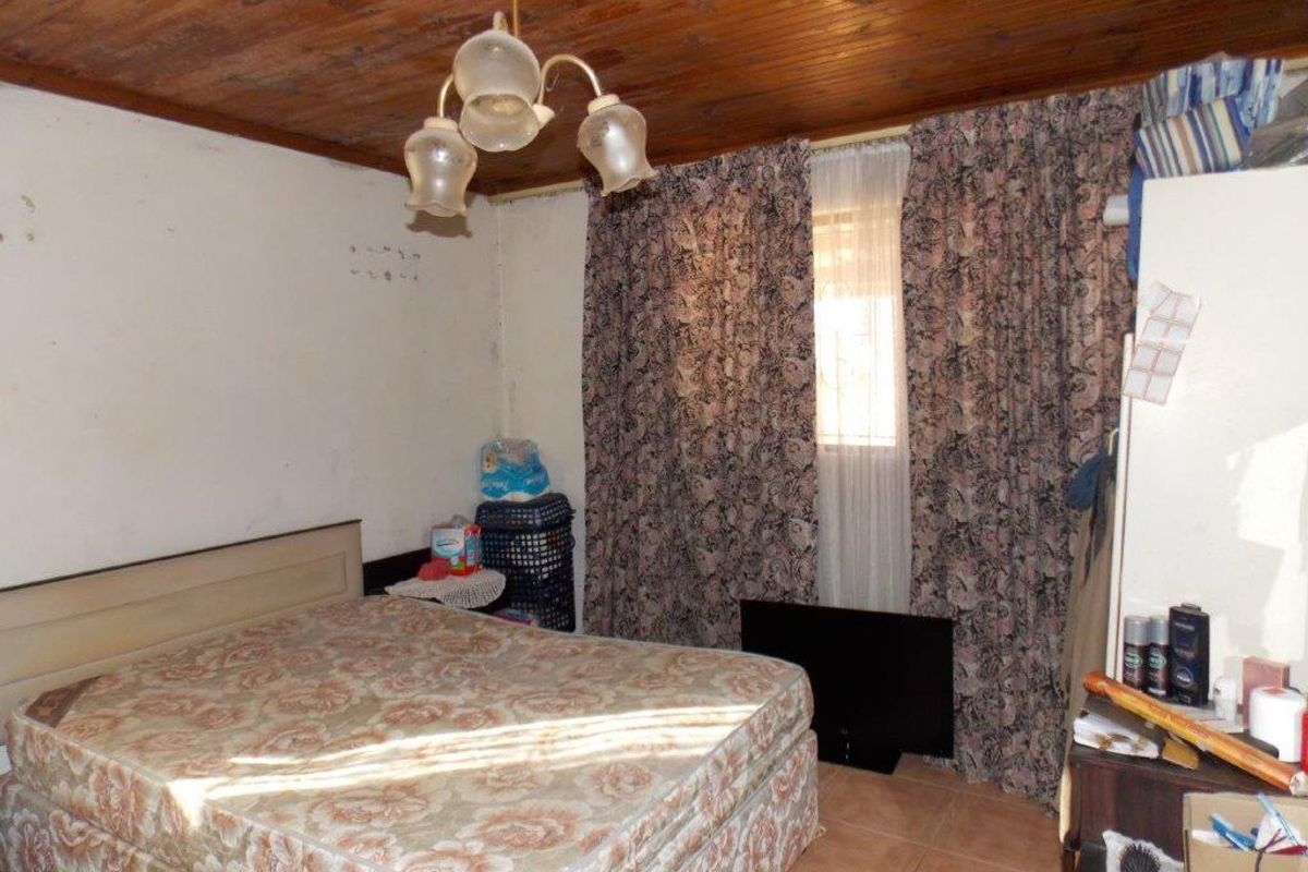 A bedroom featuring a timber ceiling and tiled flooring, currently requiring cosmetic updates and wall repairs to improve its overall condition.