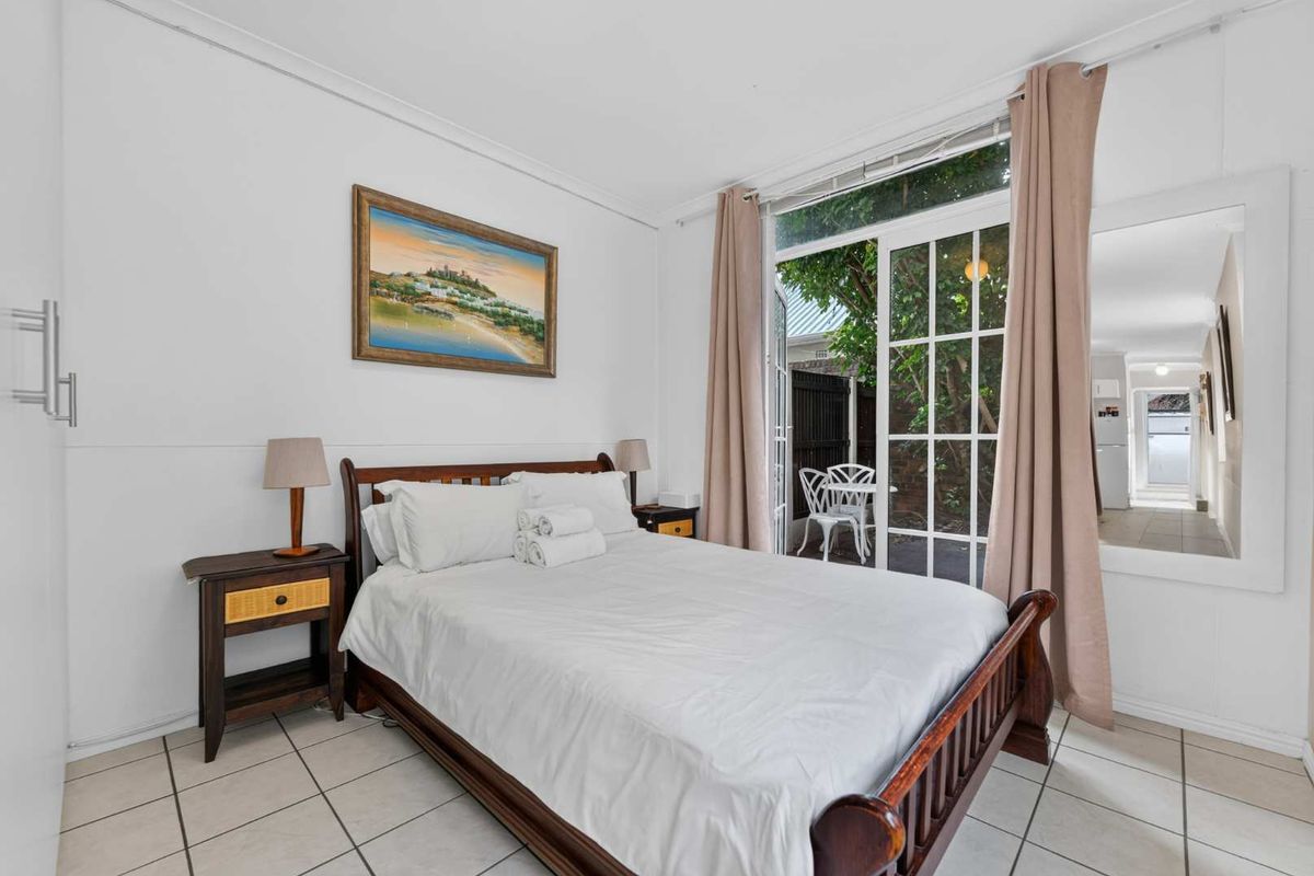 A bedroom featuring tiled flooring and a sliding glass door providing direct access to an outdoor patio area.