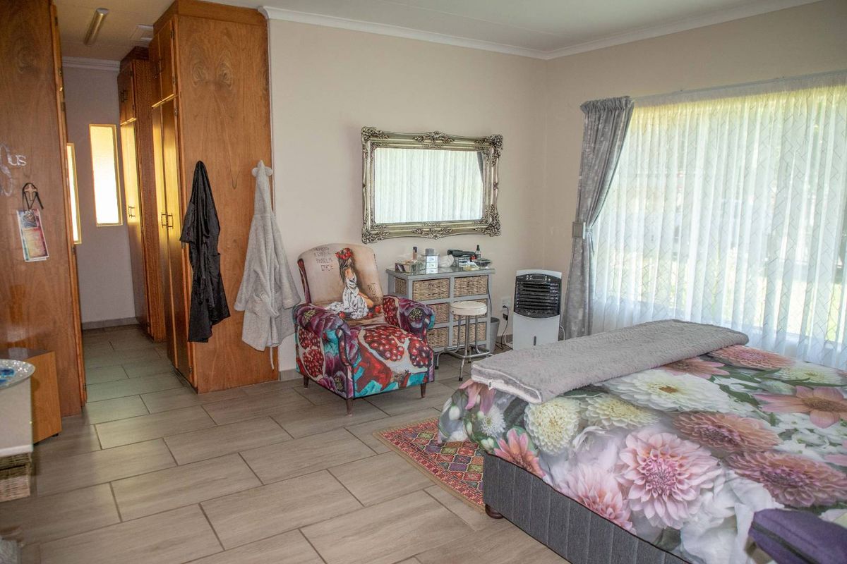 A spacious bedroom featuring built-in wooden cabinetry, tiled flooring, and large windows that provide ample natural light.