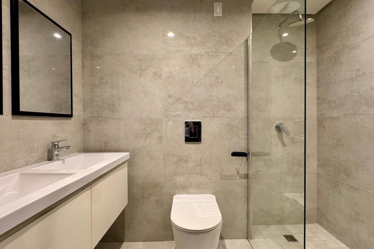 Modern bathroom featuring a wall-mounted double vanity, wall-hung toilet with concealed cistern, and a spacious walk-in shower with a glass screen.