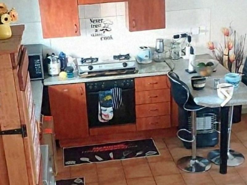 Compact kitchen featuring wooden cabinetry, built-in oven, gas cooktop, and tiled flooring.