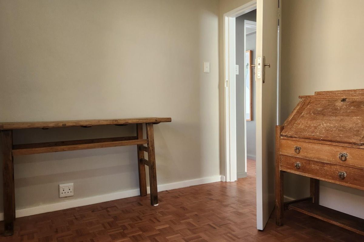 A bedroom featuring classic parquet flooring and neutral wall finishes, providing a clean and versatile space.