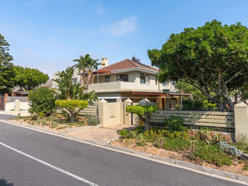 A well-maintained two-story residential property featuring a tiled roof, solar water heating system, and secure boundary wall with integrated fencing and landscaping.