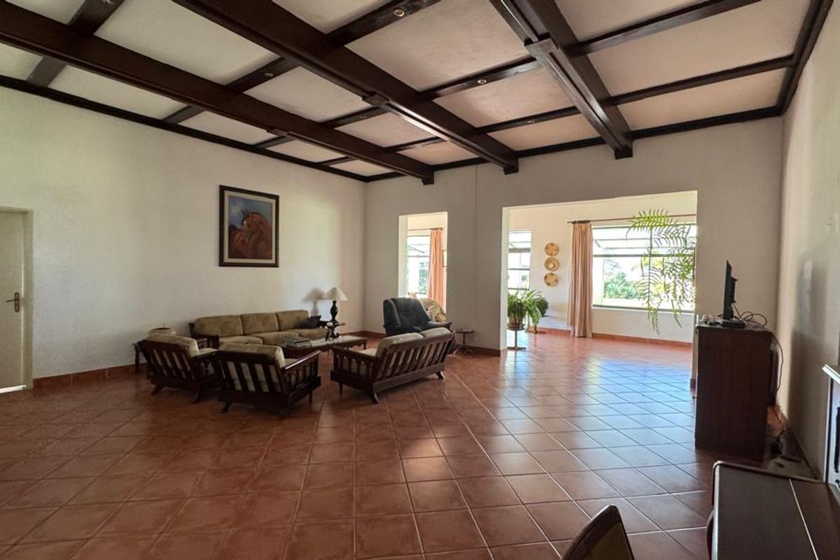 Spacious living area featuring traditional terracotta floor tiles and exposed timber ceiling beams, offering a bright and open layout with natural light.