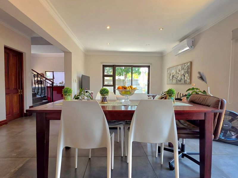 Spacious open-plan living and dining area featuring tiled floors, recessed lighting, and a wall-mounted air conditioning unit with access to the exterior.