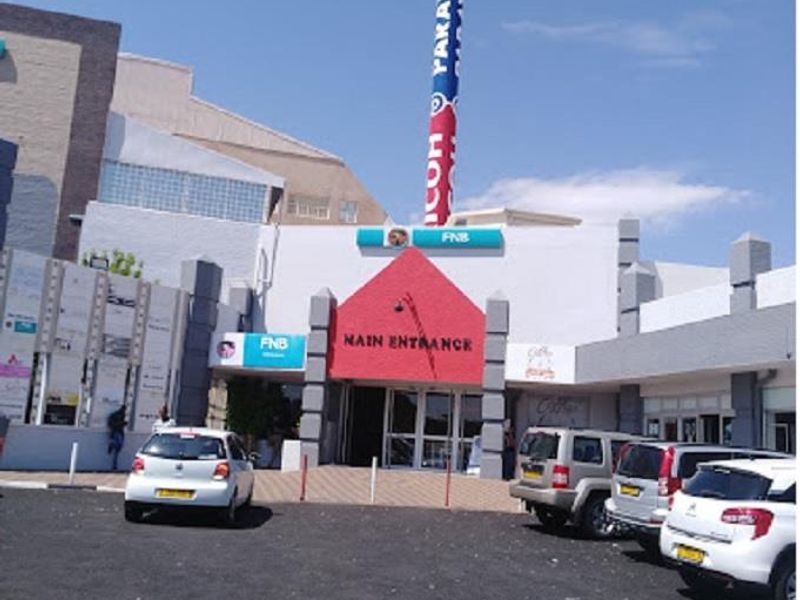 Front exterior view of the office building featuring a prominent main entrance, paved parking area, and a large telecommunications mast.