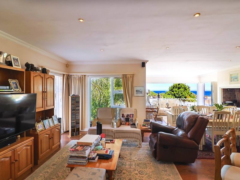 Spacious open-plan living and dining area featuring laminate flooring, recessed lighting, and a built-in fireplace, with seamless access to an outdoor patio area.