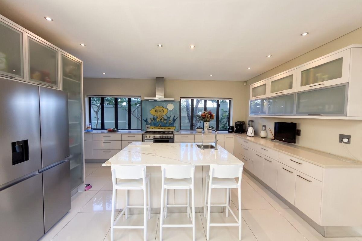 Modern kitchen featuring a central island with stone countertops, sleek cabinetry, built-in appliances, and recessed lighting, creating a bright and functional culinary space.