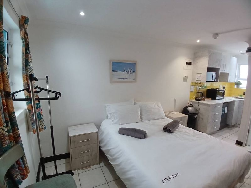 Compact open-plan studio apartment featuring a combined sleeping area and kitchenette with tiled flooring and modern cabinetry.