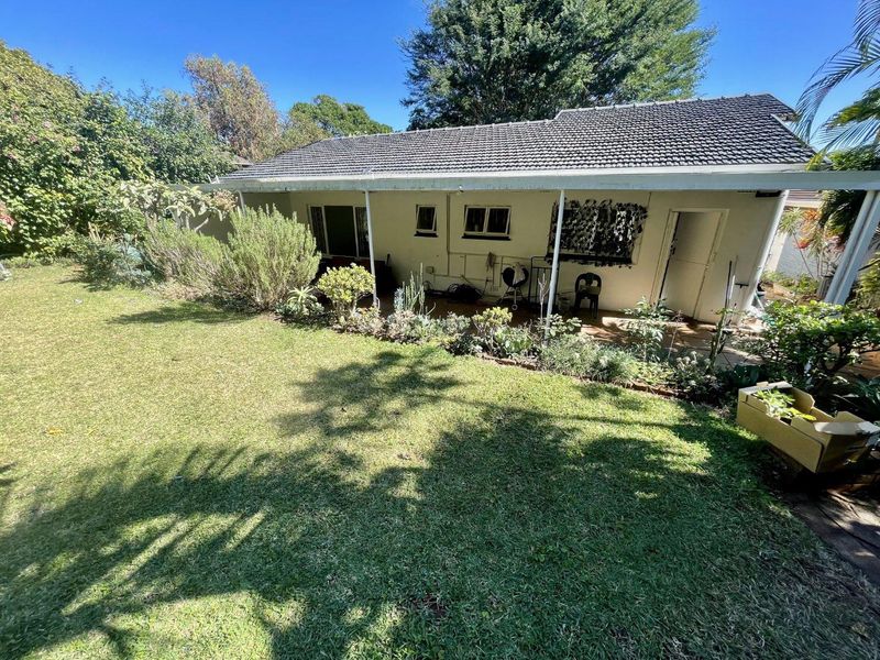 Rear view of the house featuring a covered patio area overlooking a well-established garden and lawn.