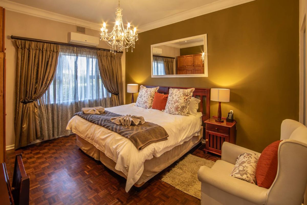 A well-maintained bedroom featuring classic parquet flooring, crown molding, and a wall-mounted split-system air conditioner.