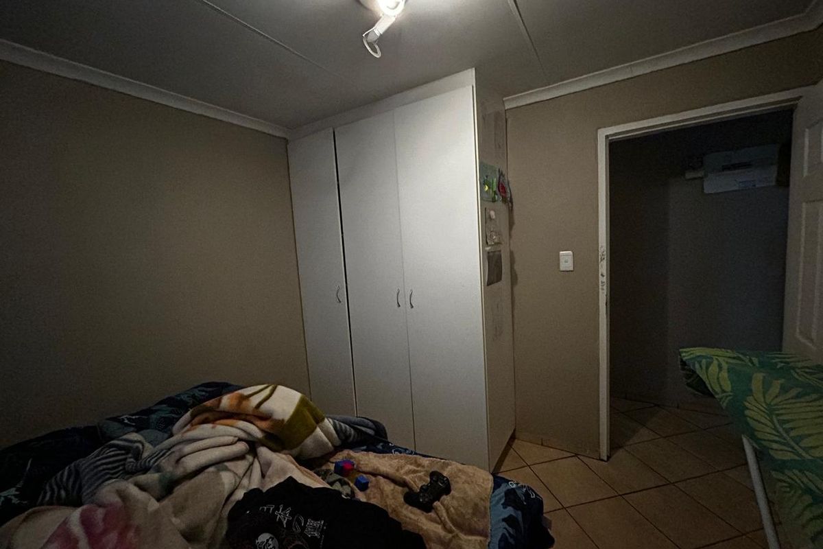A bedroom featuring built-in wardrobes, tiled flooring, and cove cornicing, requiring minor maintenance to the door frame and lighting fixtures.