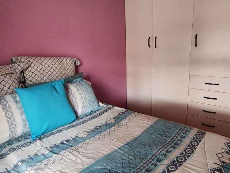 A bedroom featuring a built-in wardrobe with integrated drawers and coving detail.