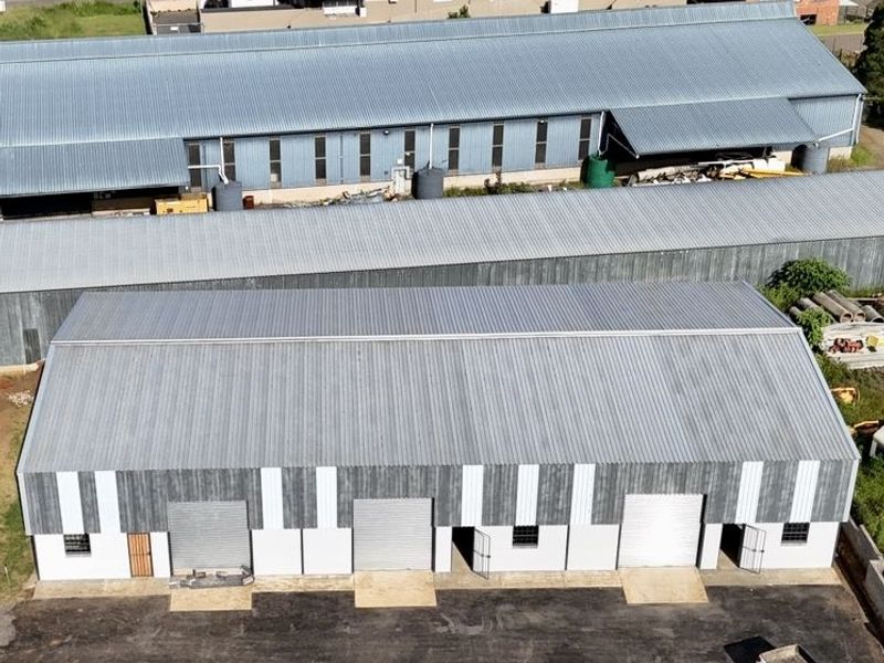 Aerial view of an industrial warehouse complex featuring multiple metal-roofed units, roller shutter doors, and a paved yard area.