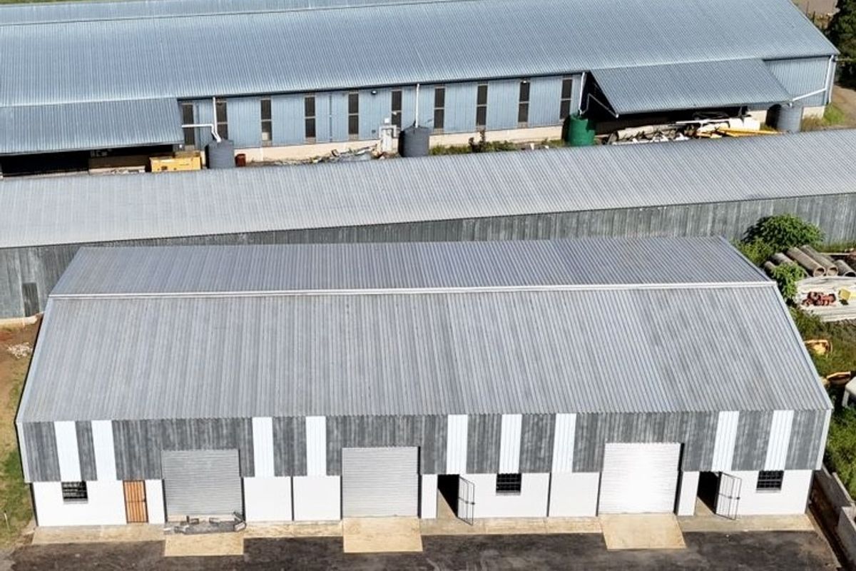 Aerial view of an industrial warehouse complex featuring multiple metal-roofed units, roller shutter doors, and a paved yard area.