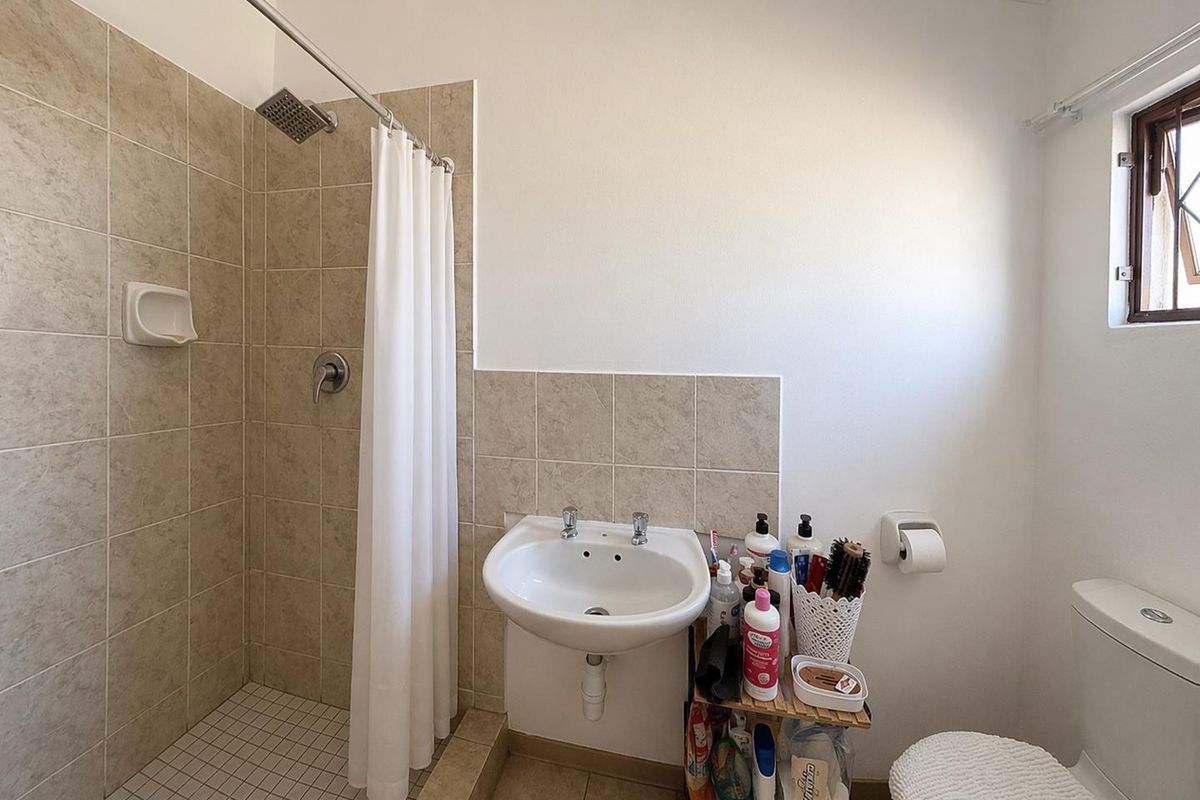 A functional bathroom featuring a walk-in shower with tiled surround, a wall-mounted basin, and a standard toilet.