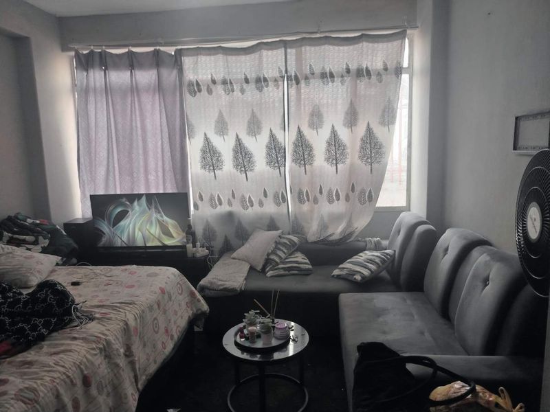 A living area featuring a large window with curtains, providing natural light to the space.