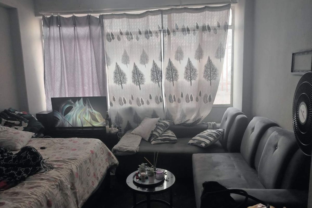 A living area featuring a large window with curtains, providing natural light to the space.