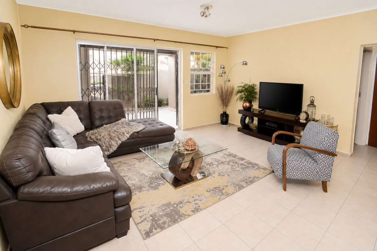 A well-lit living room featuring ceramic floor tiles, neutral walls, and a sliding glass door providing access to the outdoor area.