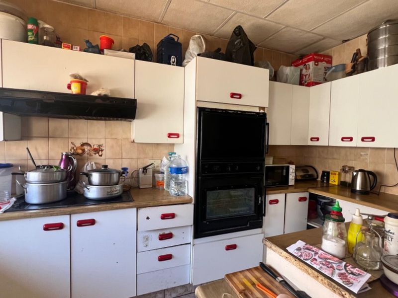 A functional kitchen featuring built-in cabinetry, a double oven, and tiled backsplash, offering potential for modernization and cosmetic updates.