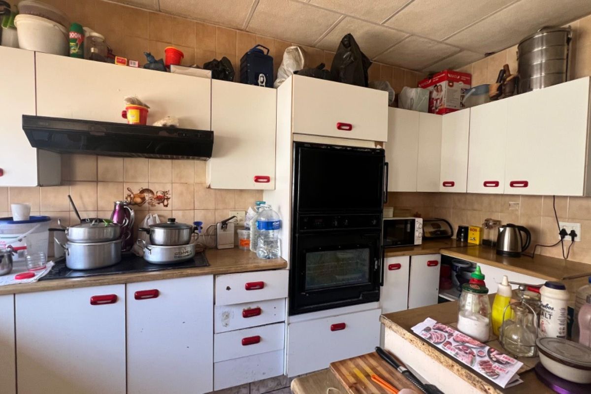 A functional kitchen featuring built-in cabinetry, a double oven, and tiled backsplash, offering potential for modernization and cosmetic updates.