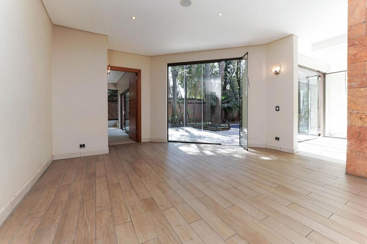 Spacious living area featuring wood-look tile flooring, recessed lighting, and large glass doors opening to a private garden.