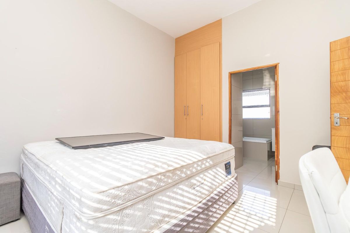 A bedroom featuring built-in wooden wardrobes, tiled flooring, and direct access to an en-suite bathroom.