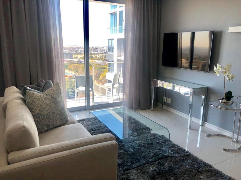 Modern living room featuring tiled flooring and large sliding glass doors leading to a balcony with city views.