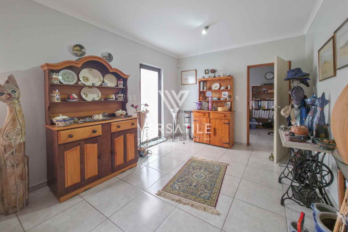 A bright living area featuring neutral tiled flooring, clean wall finishes, and a glass door providing access to the exterior.