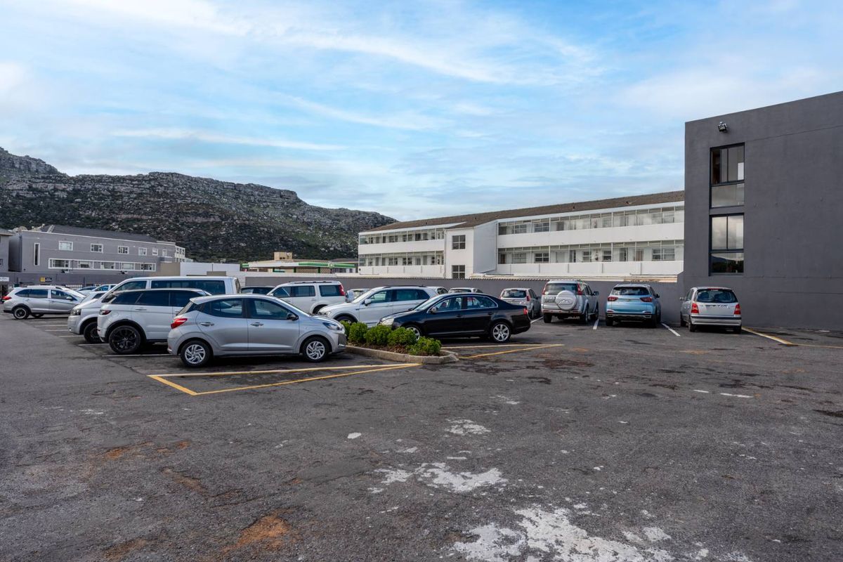 Exterior view of the apartment complex parking area featuring an asphalt surface and multi-story building facade.