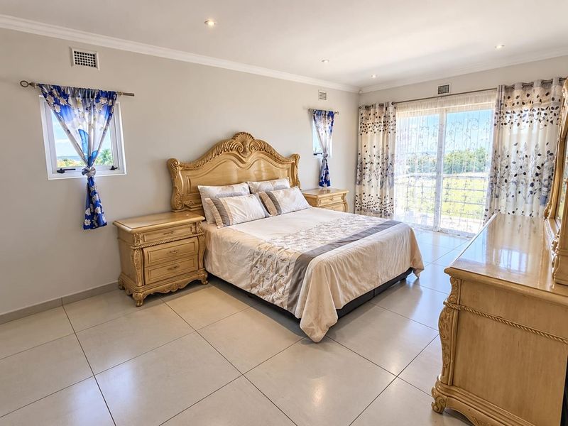 Spacious bedroom featuring neutral ceramic floor tiles, recessed downlighting, and a large sliding glass door providing access to an outdoor balcony area.