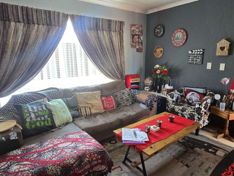 A living room featuring a large window with curtains and a dark accent wall, providing a functional space for relaxation.