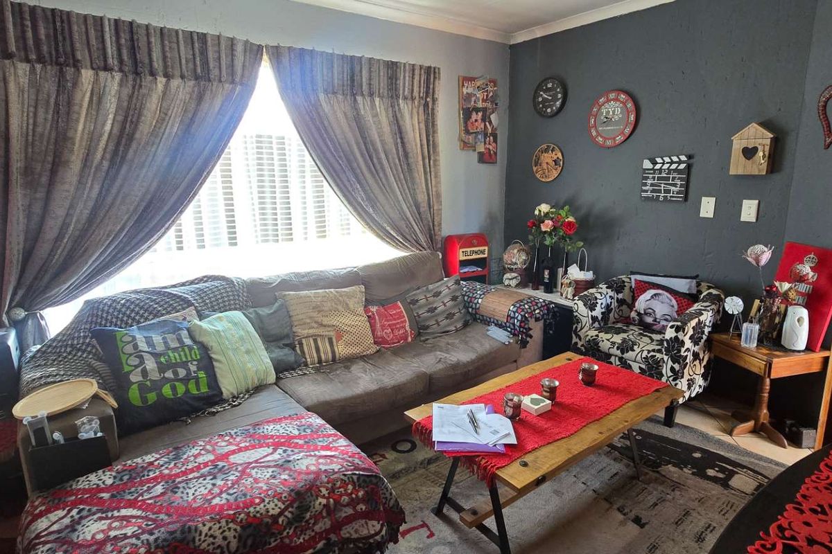 A living room featuring a large window with curtains and a dark accent wall, providing a functional space for relaxation.