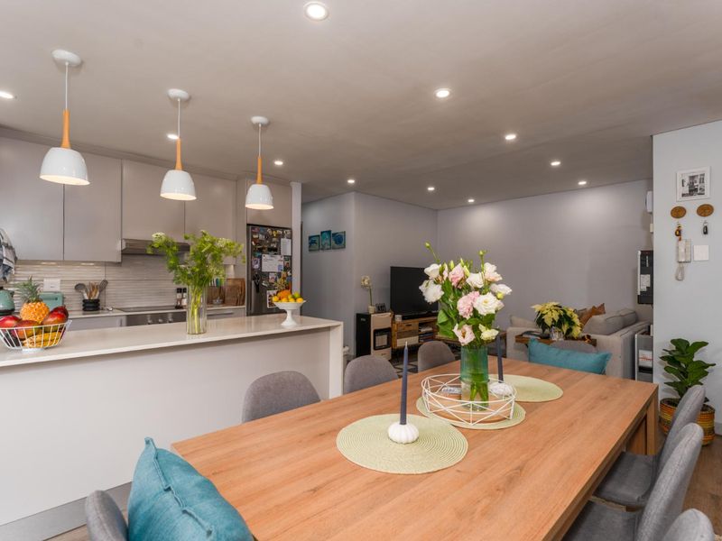 Modern open-plan living area featuring a sleek kitchen with island, pendant lighting, and integrated appliances, seamlessly flowing into the dining and lounge space.