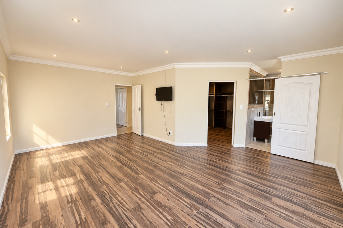 Spacious bedroom featuring laminate flooring, recessed lighting, a walk-in closet, and an en-suite bathroom with a sliding barn door.