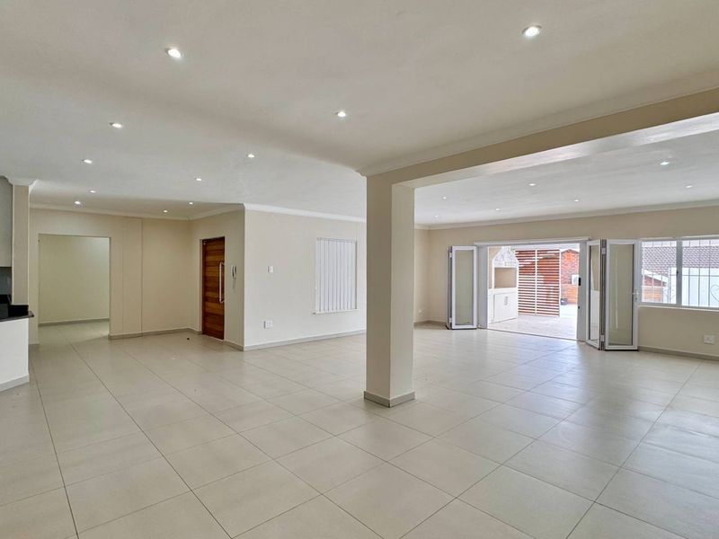 Spacious open-plan living area featuring tiled floors, recessed lighting, and seamless flow to an outdoor patio through bi-fold doors.