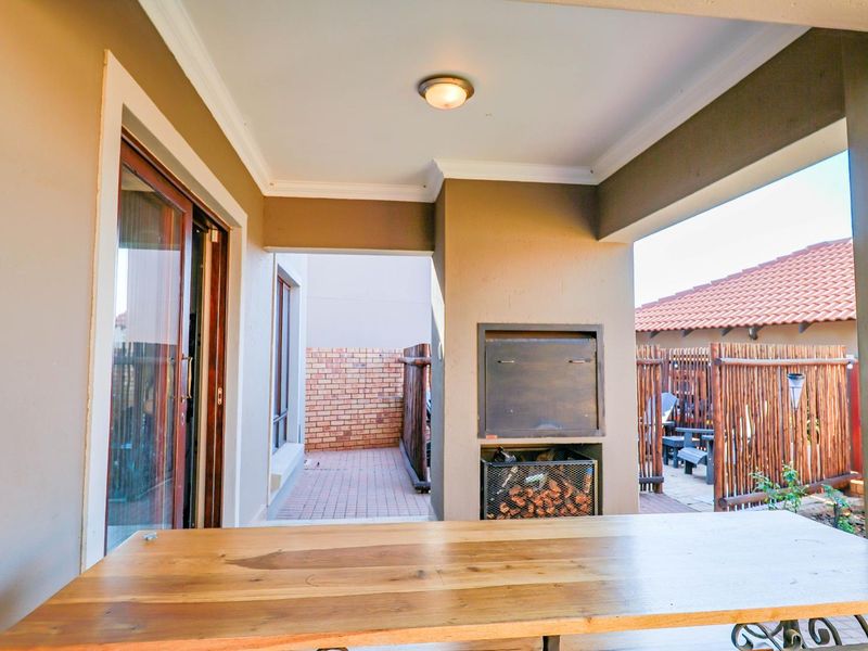 Covered patio area featuring a built-in braai, paved flooring, and direct access to the home through sliding glass doors.